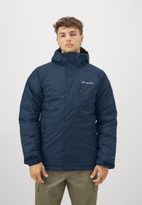 Marineblaue isolierte Jacke mit einer Reißverschlusstasche auf der Brust, verstellbarem Kapuze und elastischen Bündchen. Hergestellt aus wasserabweisendem Material.