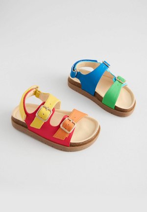 Kolorowe sandały z syntetycznymi paskami w kolorach czerwonym, niebieskim, zielonym, żółtym i pomarańczowym, z dwoma klamrami i brązową teksturowaną podeszwą.