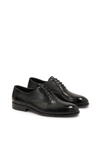 Scarpe da dress in pelle nera con una finitura liscia, punta arrotondata e chiusura con lacci a cinque occhielli. Presentano un tacco basso e lucido e cuciture minime.