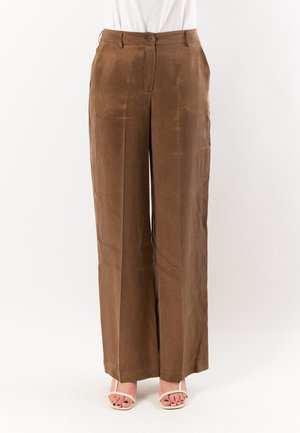 Pantaloni marroni a vita alta e gamba larga con chiusura frontale con bottone e zip, indossati con top bianco e sandali beige open toe.