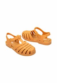 Sandali in plastica arancione, modellati, con un design intrecciato, cinturino alla caviglia regolabile, suole piatte e soletta testurizzata. Design minimalista per un look casual.