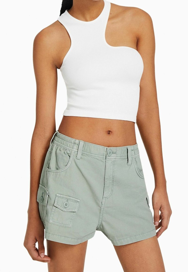 Vitt ribbat kort topp med design för ena axeln, matchat med ljusgröna cargoshorts med sidfickor och elastisk midja.