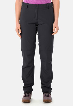 Rechte zwarte buitenbroek gedragen door een persoon met ontspannen handen langs het lichaam, gecombineerd met paarse wandelschoenen en een paarse top.