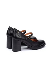 Chaussures à talons en cuir noir avec un bout rond, deux brides sur le devant, et un talon épais. Présente un petit accent doré. Texture lisse.