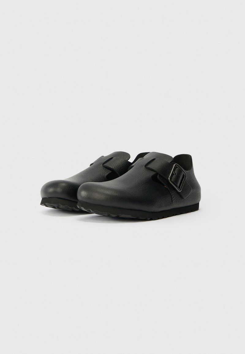 Schwarze Schuhe mit einer glatten, strukturierten Oberfläche, entworfen mit einem breiten Schnallenriemen und einer flexiblen, robusten Sohle für optimalen Halt.