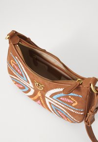 Smešani smeđi suede crossbody džep sa šarenim cvjetnim vezom u ružičastoj, plavoj i bijeloj boji. Ima zatvaranje na munju i zlatne hardverske detalje.