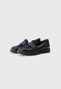 Marineblauwe loafers, gemaakt van een combinatie van glad leer en gestructureerde stof, met een decoratieve band en een chunky zool.