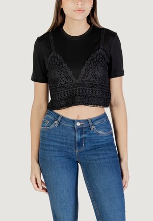 Maglietta nera corta con maniche corte, caratterizzata da un design in pizzo e ricami dettagliati sulla parte anteriore. Abbinata a jeans blu.