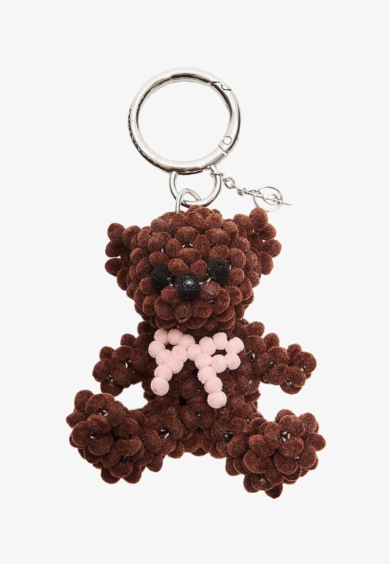 Brown teddy bear keychain made of textured pom-poms, featuring black plastic eyes and a light pink bow. Metal ring for attachment.