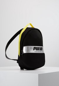 Mochila de malla negra con forma curvada, una correa amarilla brillante y una banda plateada con "PUMA WORLDWIDE" en letras negras en negrita.
