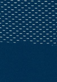 Tessuto di un blu navy con una texture, caratterizzato da piccoli punti bianchi disposti diagonalmente in modo uniforme, creando un motivo delicato sulla superficie.