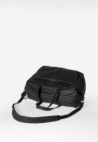 Schwarze Duffel-Tasche mit zwei Griffen und verstellbarem Schultergurt, aus strukturiertem Synthetikmaterial gefertigt, mit einer Reißverschlusstasche oben.
