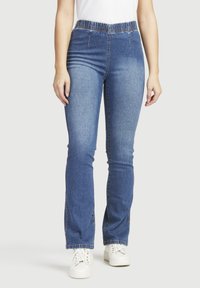 Blå denimjeans med hög elastisk midja, rak bendesign, ljus blekning och sidsömssömmar. I hop med vita sneakers.