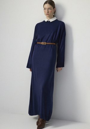 Abito lungo navy a maniche lunghe con colletto bianco, cintrato in vita con una cintura marrone. Tessuto testurizzato, fino al pavimento, vestibilità comoda.