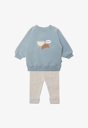 Blue cotton sweatshirt with croissant and cup graphic, paired with pale gray leggings featuring rolled cuffs. Soft texture, casual fit.