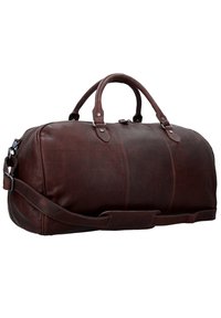 Sac de voyage en cuir marron avec des poignées doubles et une bandoulière réglable. Il présente une texture lisse et de subtils détails de couture.