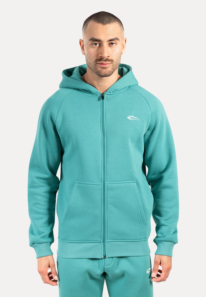 Turquoise ritsjack met een voorzak en ribgebreide mouwen, voorzien van een wit logo op de borst, gemaakt van een zachte, gestructureerde stof.
