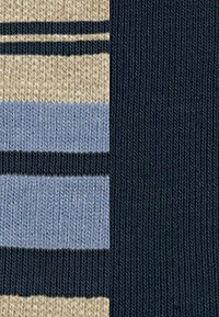Gestreifte Socken in Marineblau, Hellblau und Beige mit unterschiedlich breiten Streifen und einem strukturierten Strickmuster.