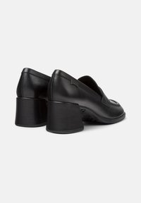 Black leather block-heeled loafers with rounded toes and branded tag on the side, shown from rear angled view on white background.