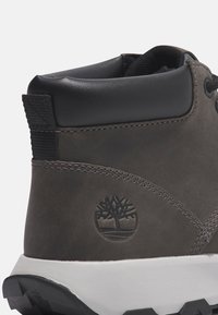 Dark gray leather ankle boot featuring a padded collar, black accents, embossed logo, and a white rubber sole with textured grip.