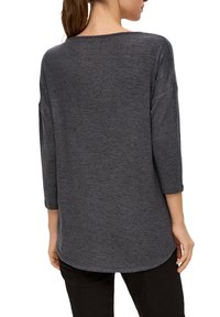 Chemise en tricot grise et texturée avec une coupe décontractée, des manches trois-quarts et un ourlet arrondi, vue de dos.