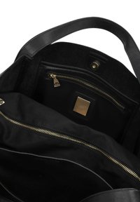 Bolso de mano de cuero negro con un acabado suave. El interior cuenta con un compartimento con cremallera y un acento de hardware en tono dorado. Diseño espacioso.