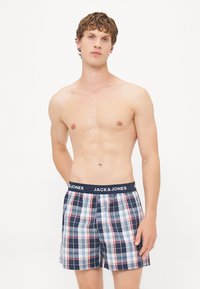 Boxershorts i blå, rød og hvit ruter; myk stoff; elastisk livlinje med "JACK & JONES"-logo. Ingen annet tøy brukes.