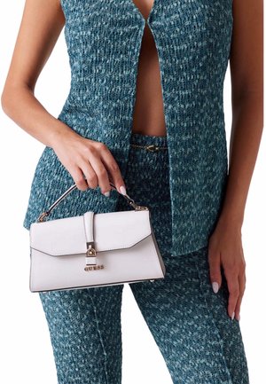 Borsa bianca con un design strutturato, dotata di manico superiore, accessori in oro e una chiusura, tenuta da una persona che indossa un outfit testurizzato blu.