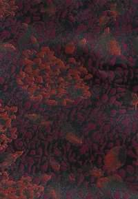 Dunkler Stoff mit komplizierter Blumenstickerei in Rot- und Burgundertönen, die detaillierte Blütenblätter und strukturierte Muster zeigt.