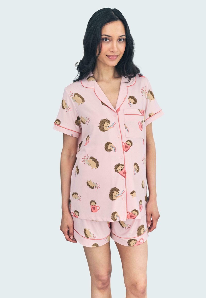 Conjunto de pijama rosa con un patrón de erizos, hecho de una tela suave con ribete rojo. Incluye una camisa de botones de manga corta y pantalones cortos.