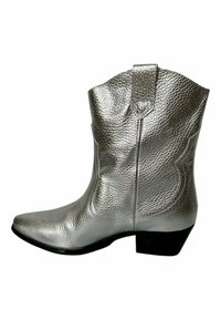 Bota vaquera plateada con un acabado de cuero texturizado, punta afilada, costuras decorativas y un tacón bajo. Cuenta con una lengüeta en el tobillo.