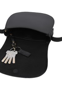 Sort lædertaske over skulderen åben, viser indvendigt med tilknyttet nøglering, der holder fem sølvnøgler.