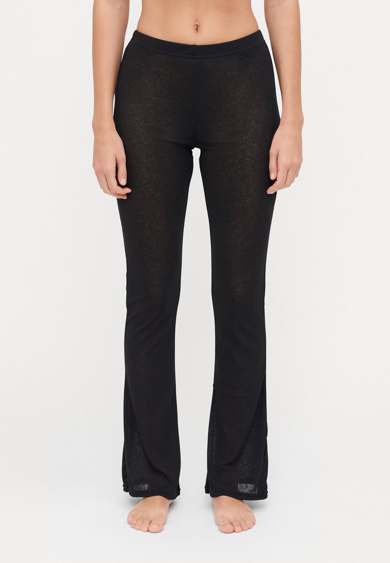 Schwarze, enganliegende Hosen aus einem leichten, halbtransparenten Stoff. Mit flachem Bund und seitlichen Schlitzen am Saum.