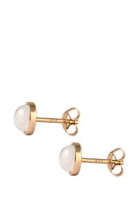 Boucles d'oreilles en métal doré, ornées d'une pierre blanche translucide de forme ronde, sertie dans une monture lisse. Le fermoir à tige dispose d'un fermoir papillon pour un port sécurisé.