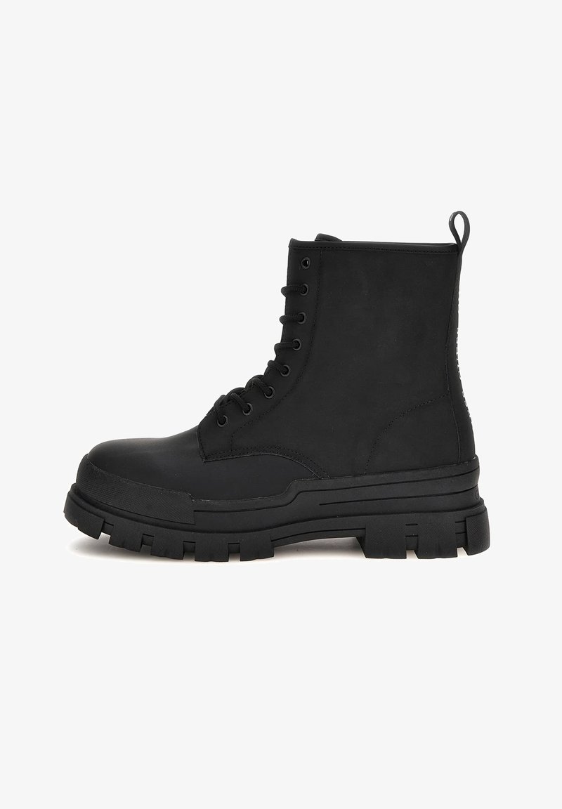 Botte de combat noire à lacets avec semelle à grosses crampons et languette à l'arrière, vue de profil sur fond blanc.