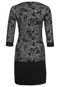 Svart klänning med trekvartslånga ärmar, prydd med ett silverfärgat paisley-mönster och en enhetligt svart underdel. Slät textur och figurnära design.