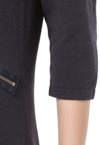 Maglione di colore blu navy a maniche corte, con un dettaglio di cerniera verticale in un tessuto a contrasto sul lato. Texture morbida.