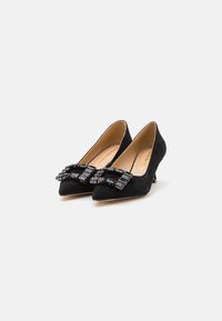Scarpe nere in suede con tacco alto e punta affusolata, dotate di una decorativa fibbia nera sul davanti. Soletta in pelle liscia.
