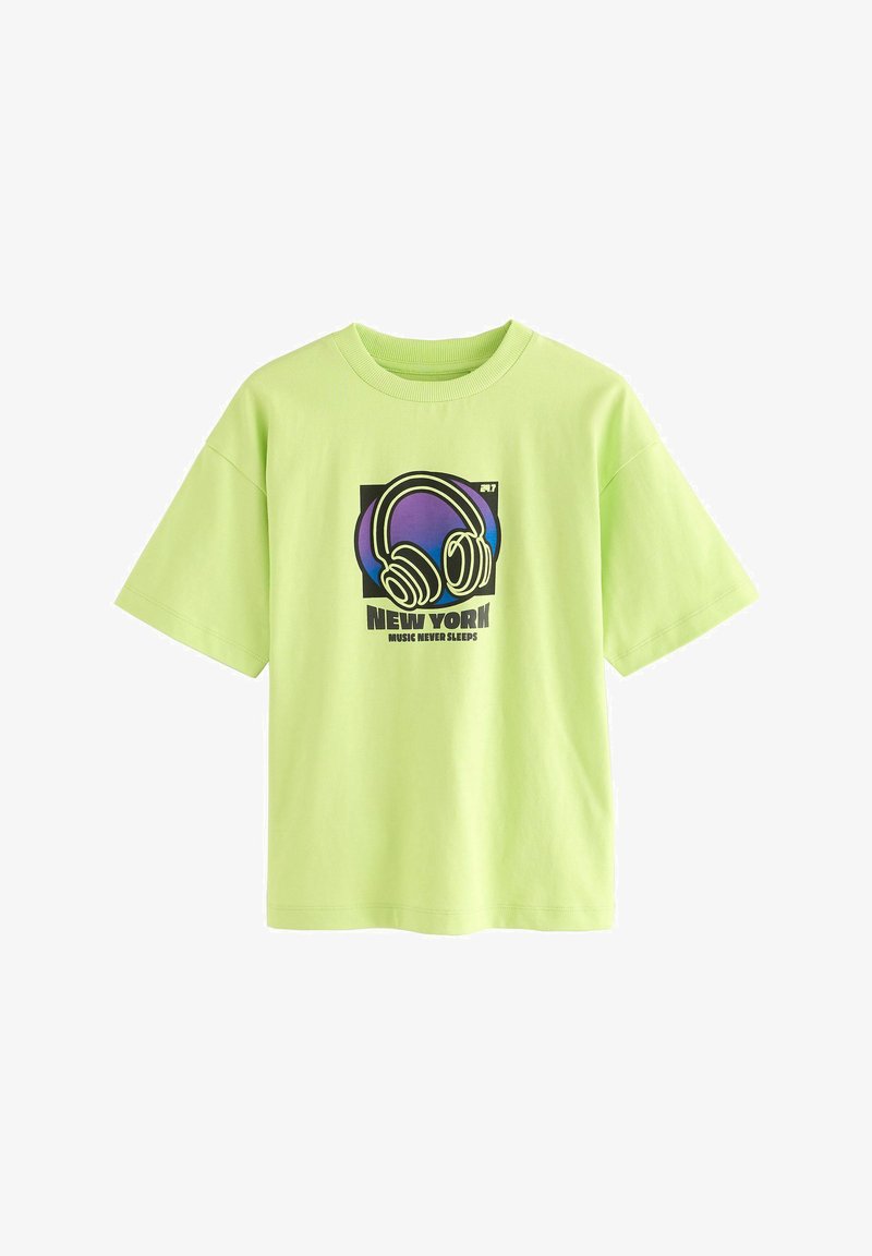 Lys grøn kortærmet t-shirt med grafik af hovedtelefoner og teksten "New York Music Never Sleeps" i sort og lilla design.