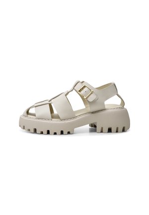 Beige åben tå sandal med brede stropper, guldspænde og chunky rillede sål set fra siden på hvid baggrund.