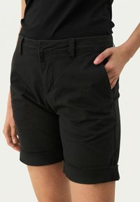 Sorte bomuldsbukser med flad front, sidelommer og oprevne manchetter. Glat tekstur og velegnet til afslappet brug.