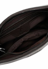 Interno di una borsa in pelle marrone con molteplici scomparti con zip, texture liscia e una fodera in tessuto scuro. Presenta un'etichetta con il logo del marchio.