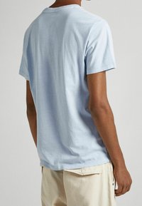 Světle modré bavlněné tričko s kulatým výstřihem a krátkými rukávy, s hladkým povrchem a volným střihem.