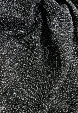 Svart tyg med en strukturerad yta som visar små silverfläckar och skapar en glittrande effekt. Materialet verkar mjukt och faller elegant.