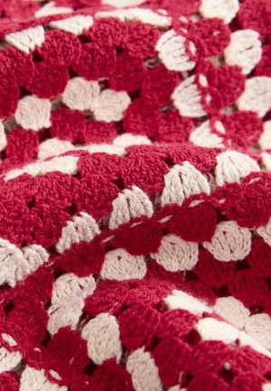 Red and cream crocheted throw blanket with a textured, geometric pattern. Soft yarn with a fuzzy finish and raised stitches.