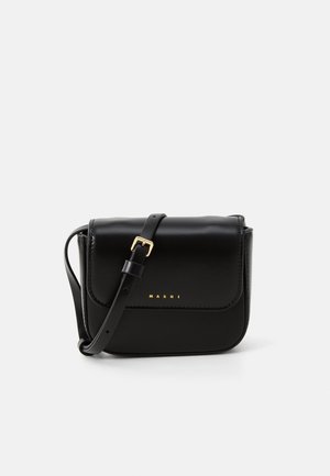 Bolso de hombro de cuero negro con un logo en relieve dorado, forma rectangular, cierre de solapa y una correa ajustable. Textura suave, diseño minimalista.