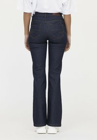 Uitlopende donkerblauwe denim jeans met contrasterende oranje stiksels, vijfzakkenontwerp en een leren patch op de tailleband.