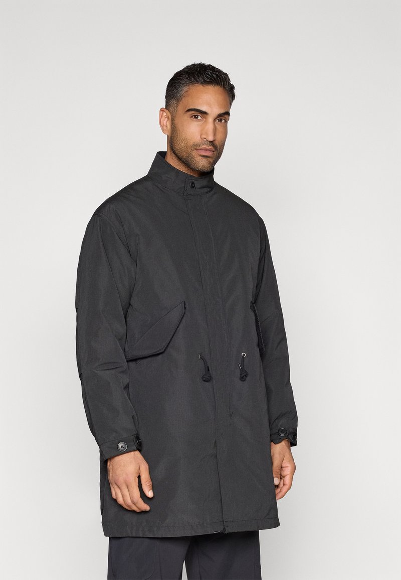 Black long jacket with high collar, front snap closure, adjustable drawstrings, and side pockets. Made from a lightweight, textured fabric.