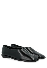 Des chaussures noires en cuir à enfiler, avec une texture lisse, un bout arrondi et un design minimaliste. Profil slim avec un talon discret.