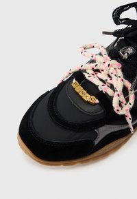 Μαύρο αθλητικό παπούτσι με συνδυασμό λείου υλικού και βελούδου. Διακοσμημένο με πολύχρωμα κορδόνια και χρυσά γράμματα που σχηματίζουν τη λέξη «PINKO». Λαστιχένια σόλα.